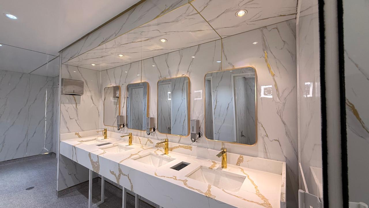 High‑end restroom interior similar to the best portable toilets in UAE, featuring marble sinks and gold fixtures.